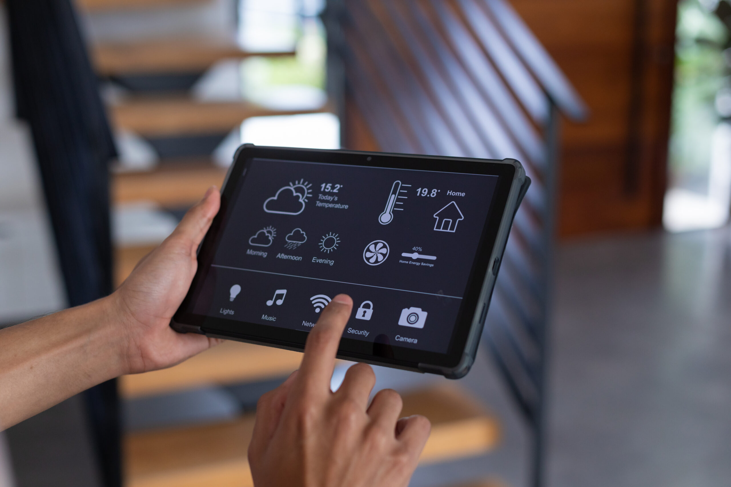 Hands of biracial man at home using tablet with smart home interface on screen. Communication, technology and domestic life concept.