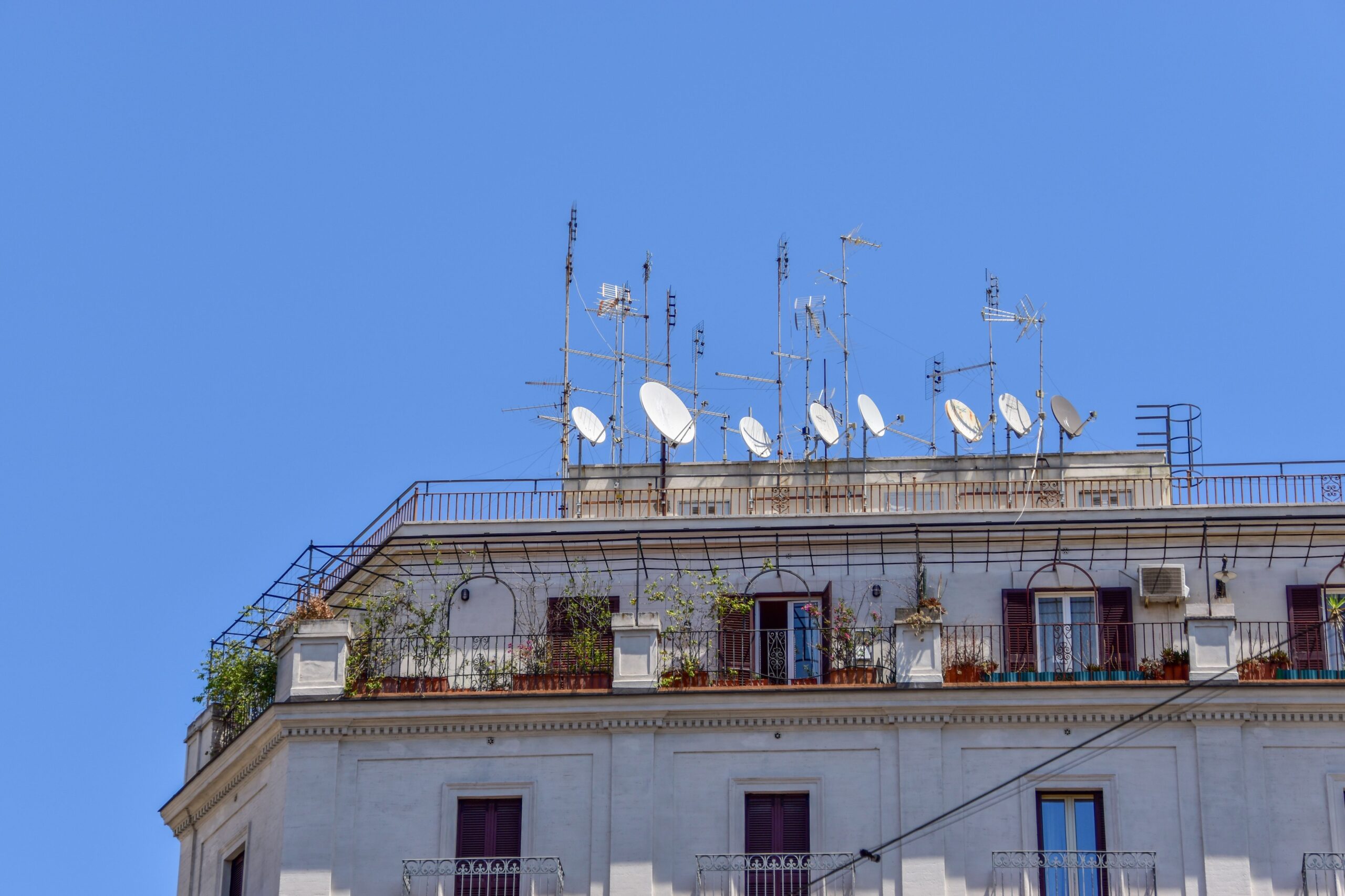 The low angle view of satellite dishes and TV antennas on the roof top of a civilians building