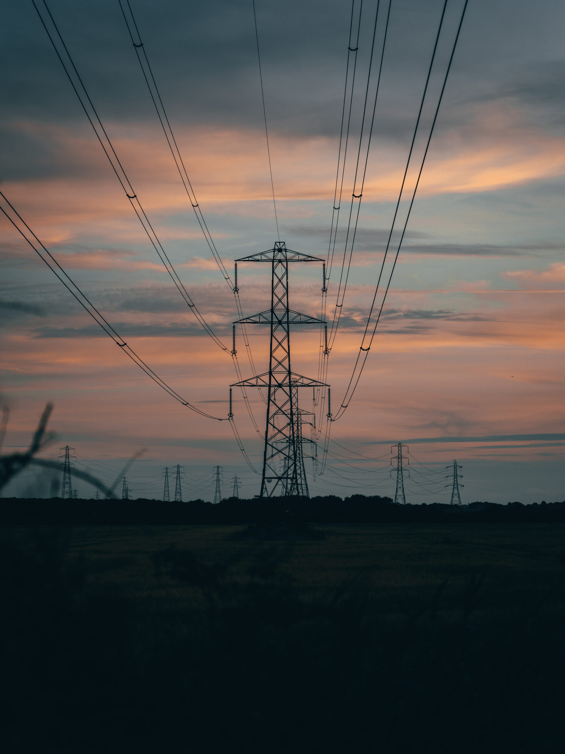 A vertical shot of transmission tower at scenic colorful sunset